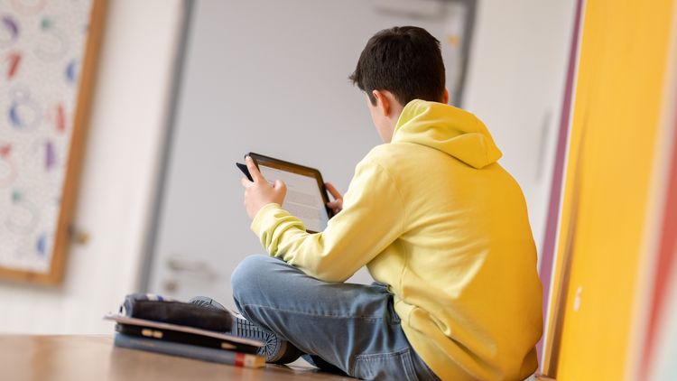 Ein Kind lernt im Schulflur an einem Tablet.