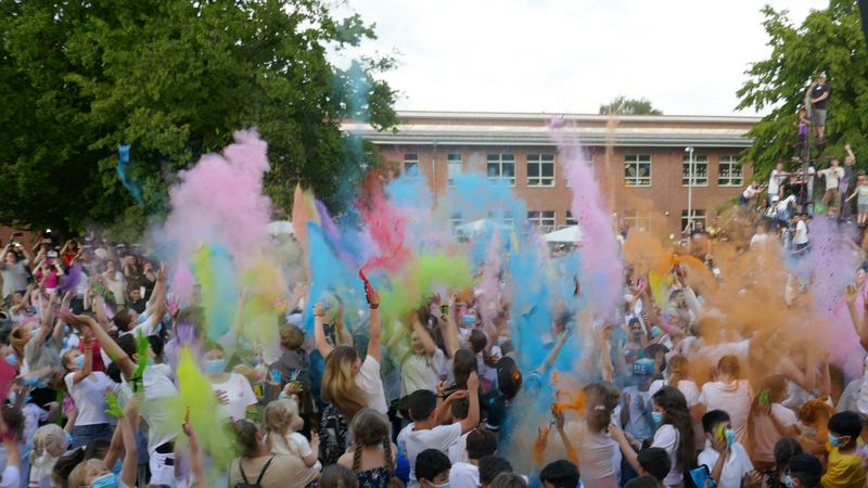 Kolorierte Maisstärke hüllt den Hof der Primus-Schule Minden beim feierlichen Schuljahresabschluss 2023 in bunten Farbenstaub.