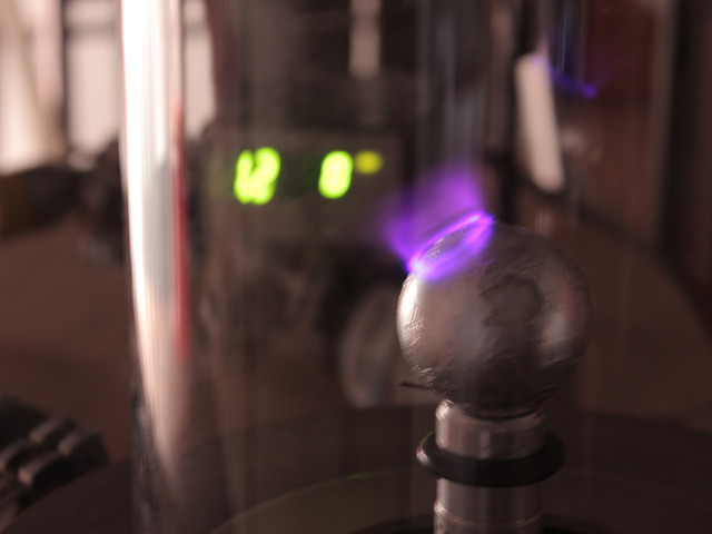 Foto einer Metallkugel in einem Vakuum mit einem nachgestellten Polarlicht.