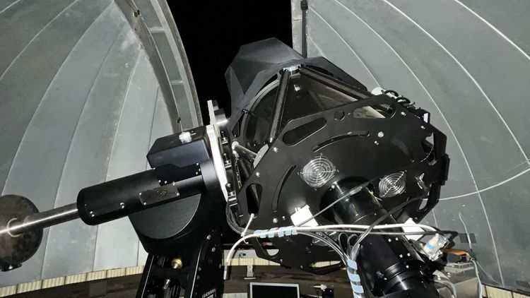 The large telescope can be seen from below, pointing at the dark sky through the observation window. 
